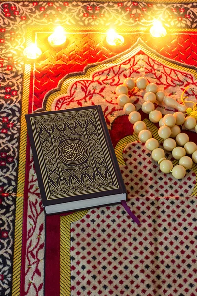 Holy Quran, rosary, and candles on the prayer mat. Ramadan time concept