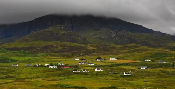 Mountain with low clouds and houses in Isle of Skye - Scotland