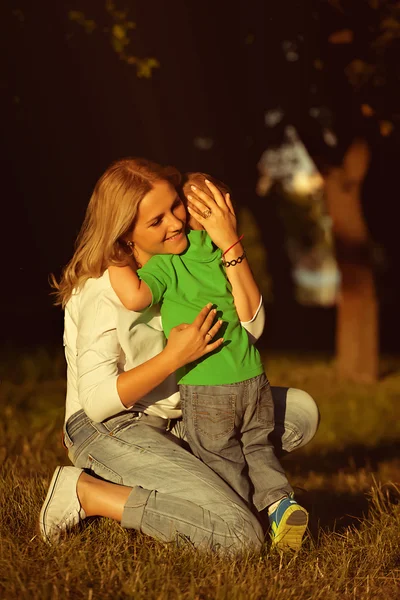 Mother hugging her son with love in park.