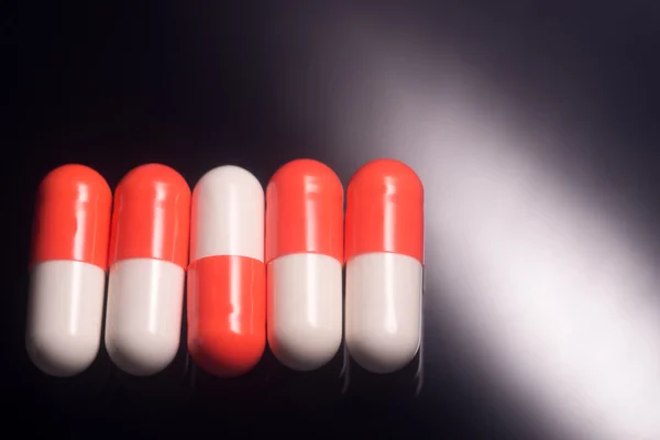 Red and white pills in a row on black background