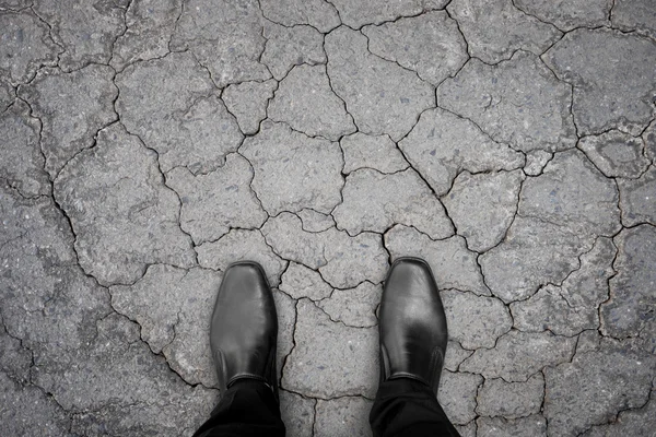 Black shoes standing on damaged asphalt concrete floor