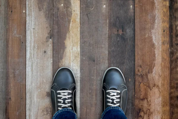 Black casual shoes standing on wooden floor