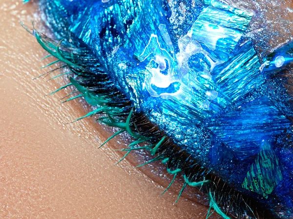 Cosmetics and make-up. Closeup macro shot of fashion sparcle visage. Closeup portrait of beautiful young woman with blue foil on face. Creative makeup.