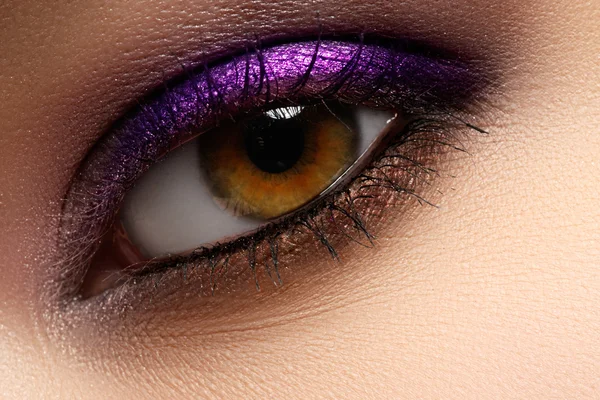 Purple shine make-up of woman eye. Woman eye with style violet and fashion make-up. Beautiful female face with bright purple fashion makeup