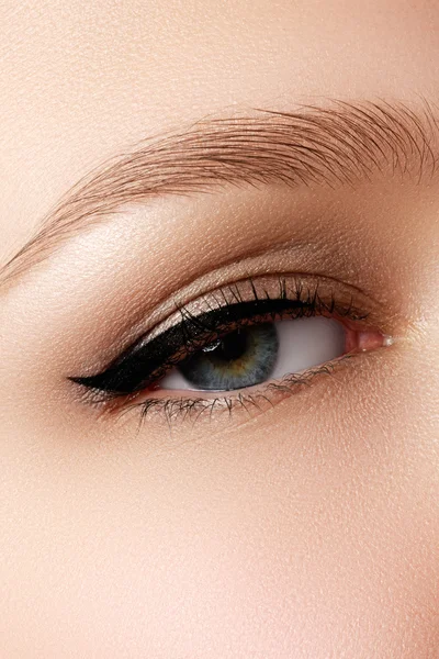 Cosmetics & make-up. Beautiful female eye with sexy black liner makeup. Fashion big arrow shape on woman\'s eyelid. Chic evening make-up