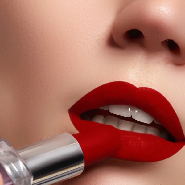 Extreme close up on model applying dark red lipstick. Makeup. Professional fashion retro make-up. dark red lipstick. Wine Lips