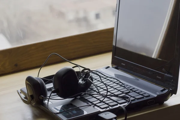 Laptop and headphones lie at the window listening to music on a