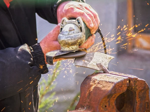 Sharpening garden tools hoe using grinder close-up, Machine for