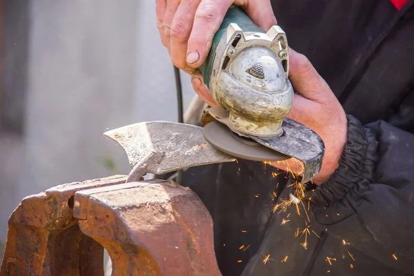 Sharpening garden tools hoe using grinder close-up, Machine for