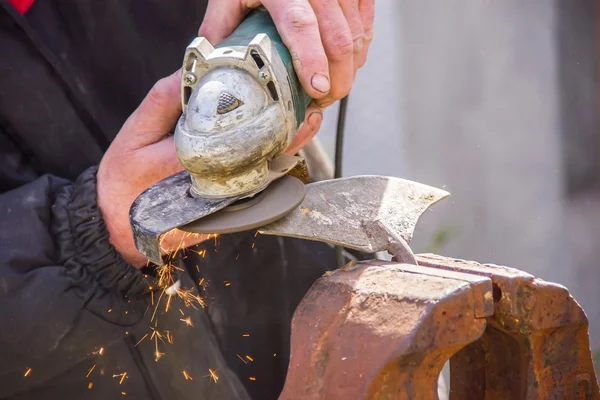 Sharpening garden tools hoe using grinder close-up, Machine for