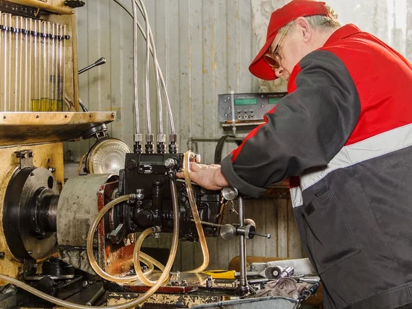 Professional mechanics testing diesel injector in his workshop,