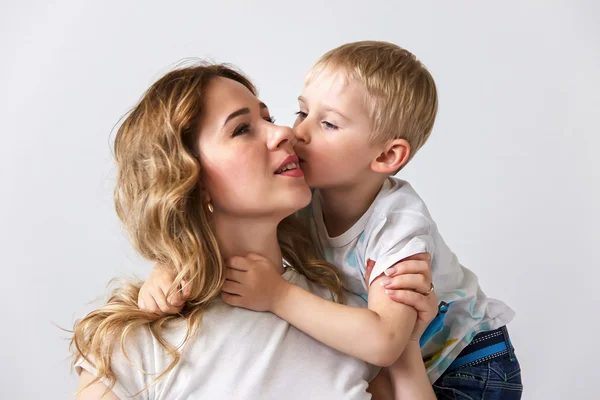 Boy kisses his mother on a white background, education of childr
