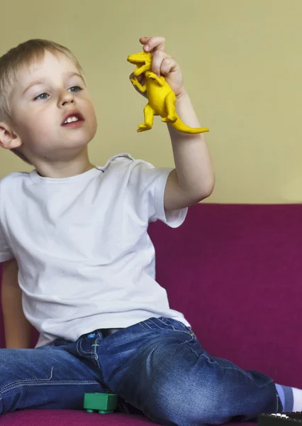 Boy holds a toy dinosaur, soft focus, focus on a dinosaur