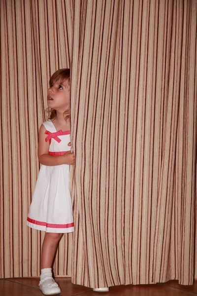 Girl hiding behind the curtain