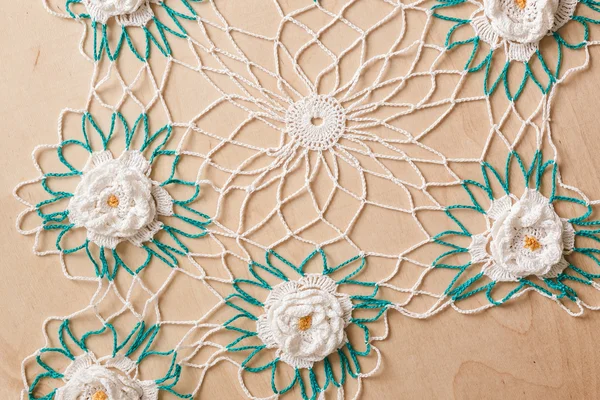 Lace doily with flowers white and green on a wooden background