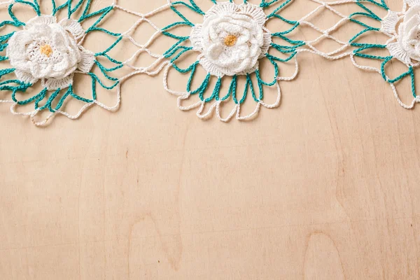 Lace doily with flowers white and green on a wooden background