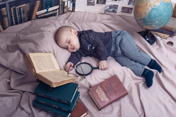 Little child scientist in glasses among the books