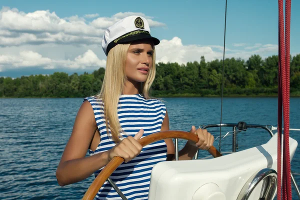 Beautiful young blonde woman at helm of ship