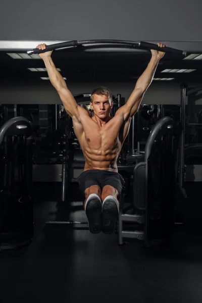 Muscular young man doing pull up on horizontal bar