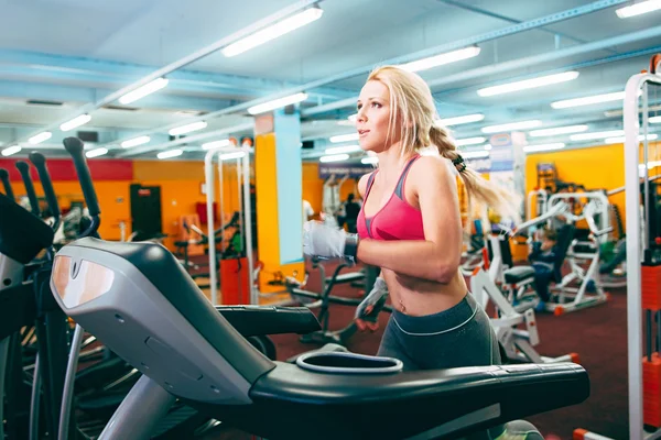 Athletic girl runs on treadmil in gym