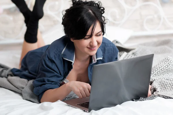 Smiling woman on bed with laptop
