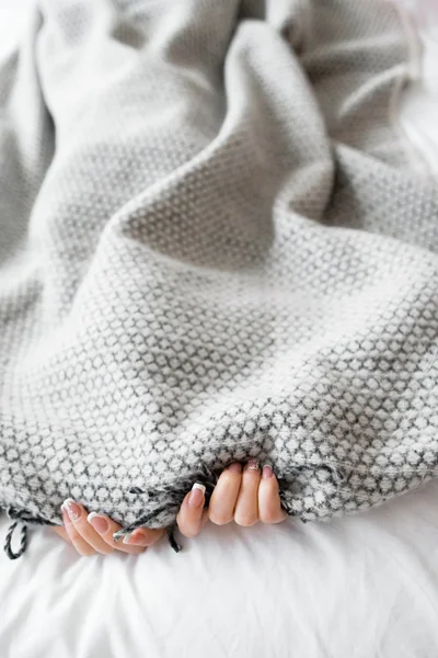 Woman hiding from the problems under gray blanket