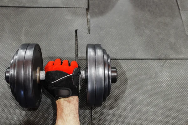 Male hand in sport glove holding dumbbell void