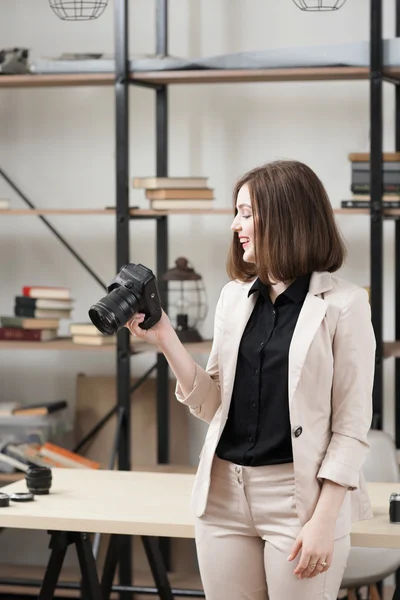 Laughing woman standing with camera at office