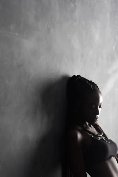 Black sad woman on a gray background.