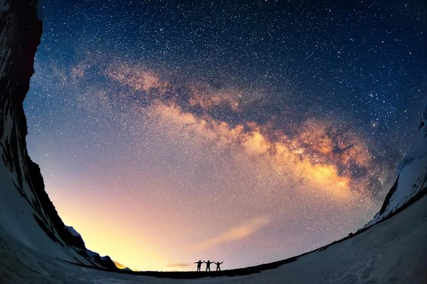 Silhouettes of people against Milky Way