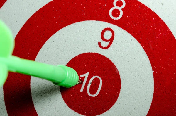 Green dart arrow hitting in the target center of dartboard