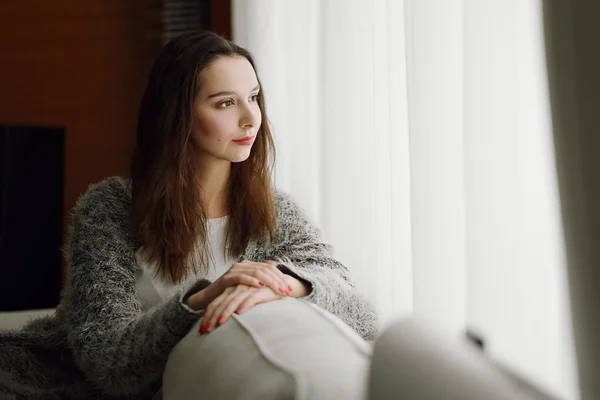 Pretty young woman looking to the window in darkness