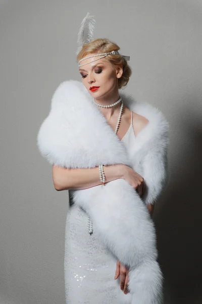 Woman in white dress with shoulder straps and long fur stole