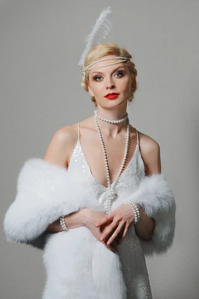 Woman in white dress with shoulder straps and long fur stole