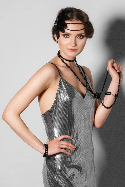 Model in retro style silver tinsel dress with plume in hair