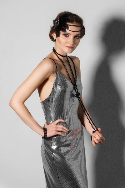 Model in retro style silver tinsel dress with plume in hair