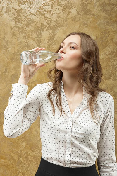 Attractive girl drinking and slopping out water on her blouse