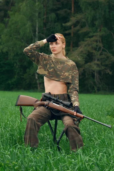 Attractive hunter girl with hunting carbine looking out the trop