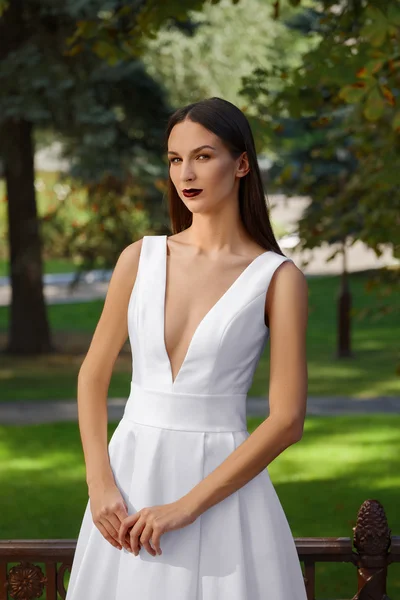 Beautiful girl in long white dress with a deep neckline. Fashion