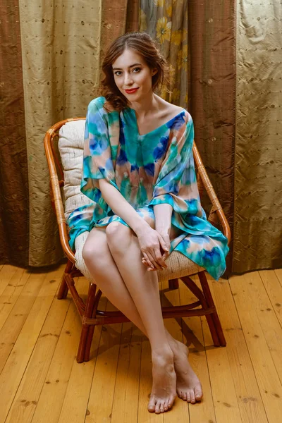 Lady sitting in armchair in silk short dress