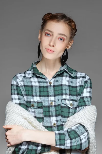 Young lady posing with crossed hands in warm cell shirt and sweater