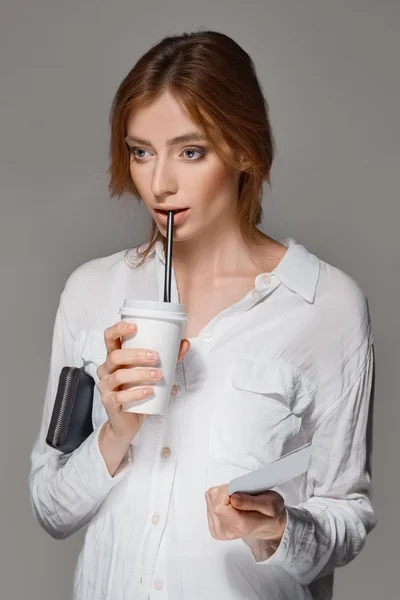 Red hair girl drinks through straw from the glass