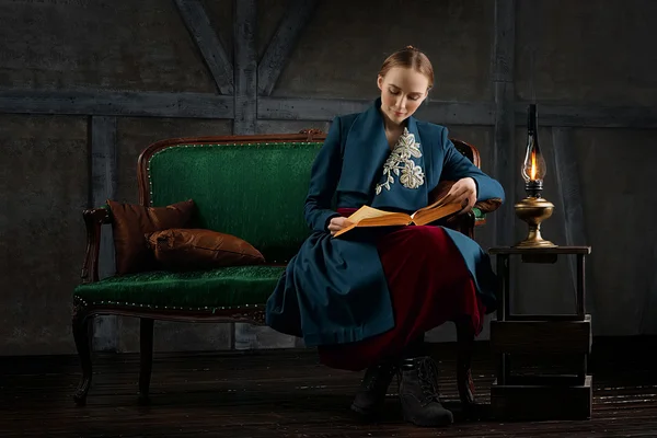 Attractive lady reading ancient book near vintage kerosene lamp