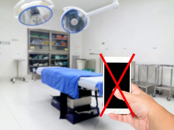 Man hand holding do not use your mobile Recording in the operating room background