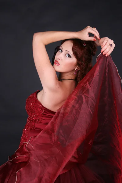 Red-haired beautiful girl dances a passionate Spanish dance studio on a dark background