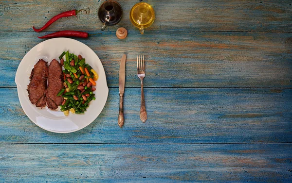 On the table is a bright plate with two pieces of meat