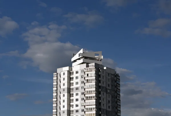 Modern residential building against blue sky with clouds.