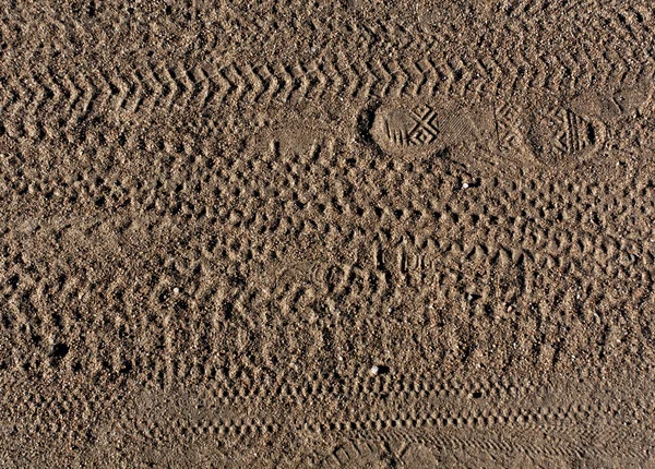 Abstract pattern of foot prints and bike tyre tracks on sand.