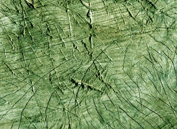Abstract green toned cut old tree surface with axe scratches.