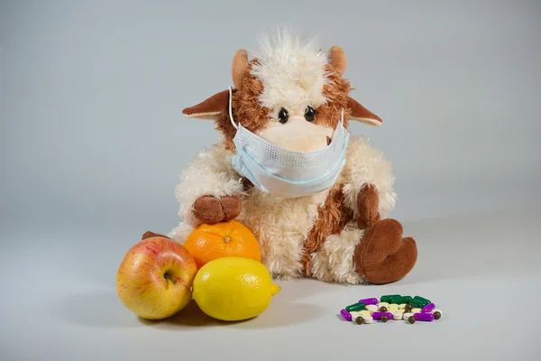 Children\'s toy bull in a medical mask with healthy fruits and va